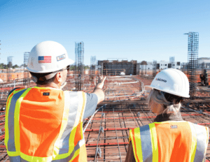 two construction workers looking over a large project